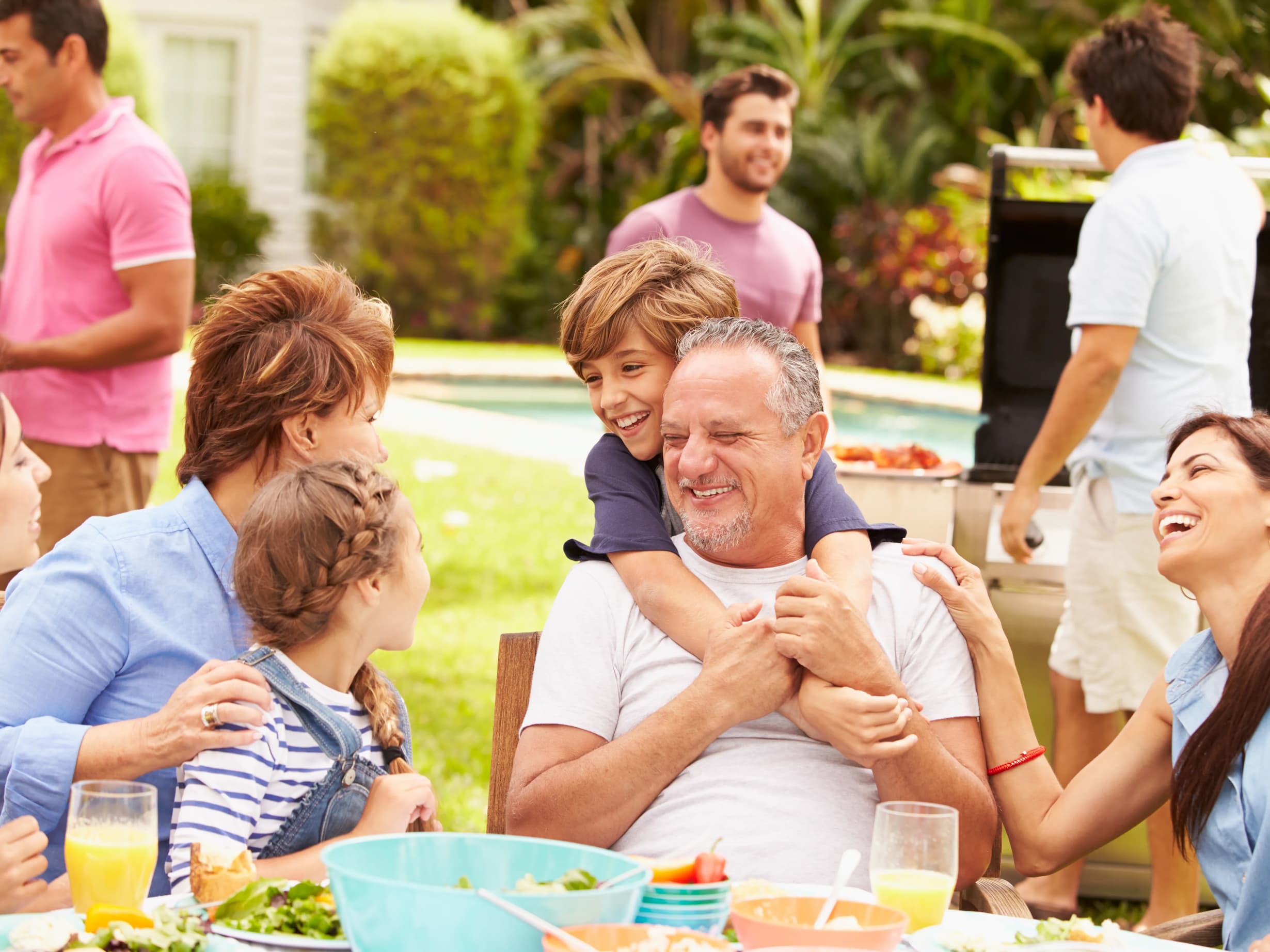 Multi generation family enjoying meal in garden together using hearing aids